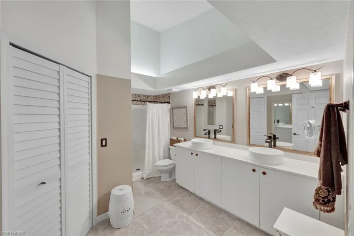 Bright en-suite bath featuring dual sinks, a walk in shower and plenty of storage.
