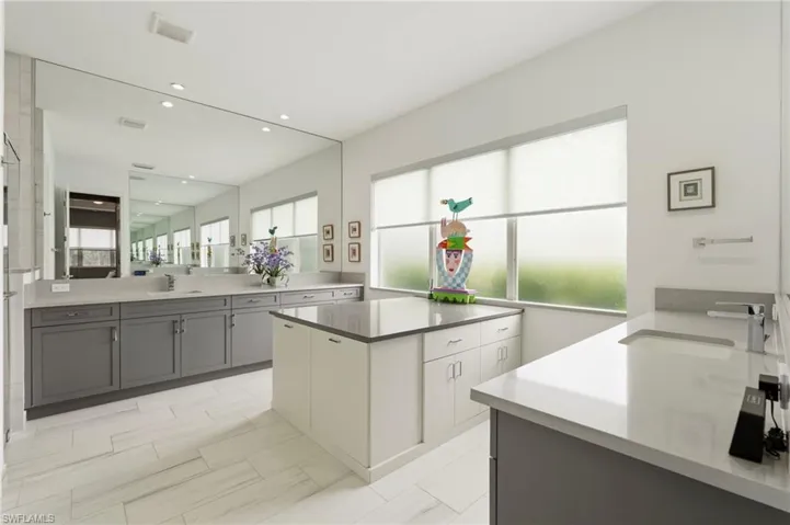 Large primary bathroom suite with dual counters, walk-in shower, storage area with built-in laundry baskets.