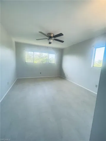 Empty room featuring ceiling fan, healthy amount of natural light, and light floors