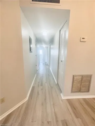 Corridor with light wood-type flooring and baseboards