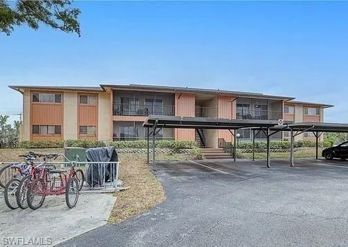 View of apartment building / complex featuring covered parking and stairs