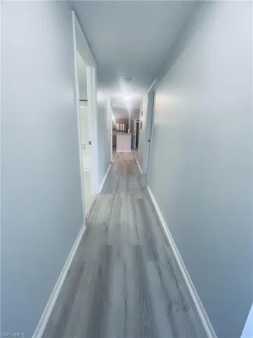 Corridor featuring baseboards and light wood-style flooring
