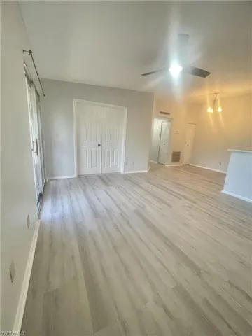 Unfurnished bedroom with light wood-style floors, hanging lights, a closet, and a ceiling fan