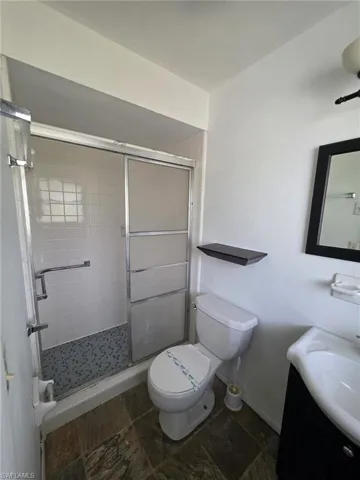 Shower enclosure with sliding frosted glass doors, white subway tile surround, and mosaic tile flooring