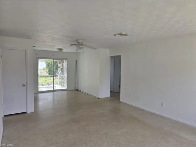 Expansive open-concept room featuring light-toned flooring, white walls, and a ceiling fan