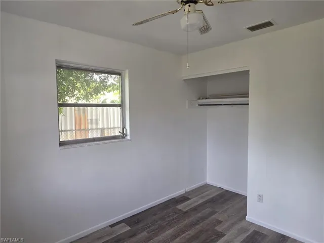 Room featuring wood-finish flooring, white walls, and a ceiling fan with integrated lighting