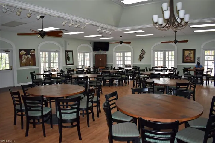 Dining space with french doors, ceiling fan with notable chandelier, rail lighting, vaulted ceiling, and light wood-type flooring