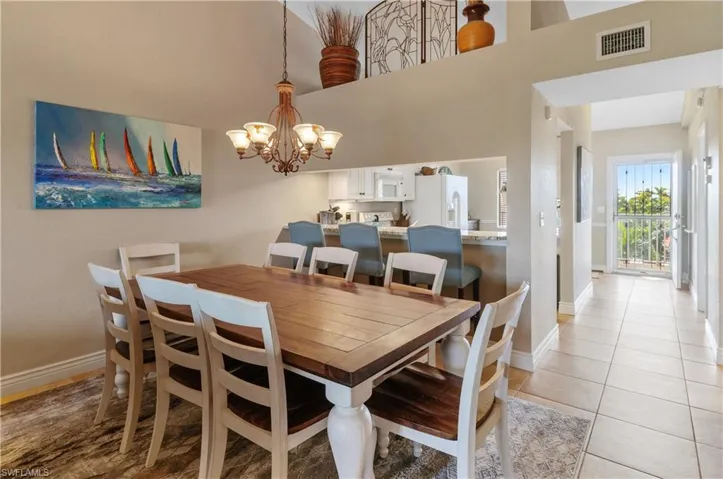 Dining room with a high ceiling, an inviting chandelier, and light tile patterned flooring