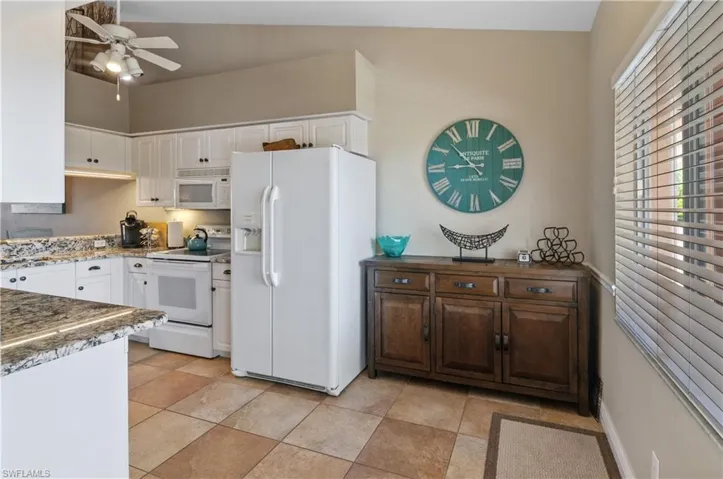 Kitchen with white cabinets, white appliances, ceiling fan, and lofted ceiling