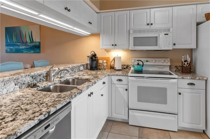 Kitchen featuring white cabinets, white appliances, and sink