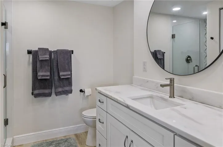 Bathroom featuring vanity, toilet, an enclosed shower, and wood-type flooring