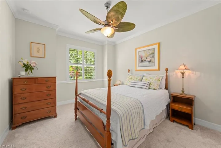 Guest bedroom with fan and window with plantation shutters
