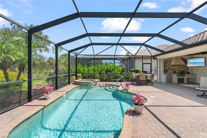 Extended lanai with pool cage, a built-in outdoor kitchen, inground swimming pool and spa and electric hurricane shutter