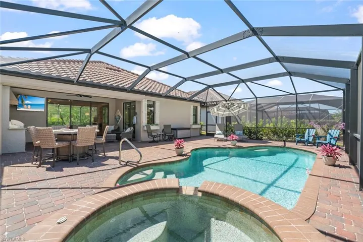 Extended lanai with pool cage, a built-in outdoor kitchen, inground swimming pool and spa