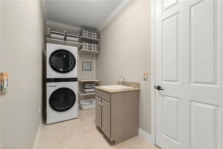 Laundry room with appliances with upper and lower storage shelving and laundry tub