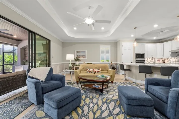 Open floor plan with the main living space with a tray ceiling, recessed lighting, kitchen with quartz countertops, and white cabinetry.