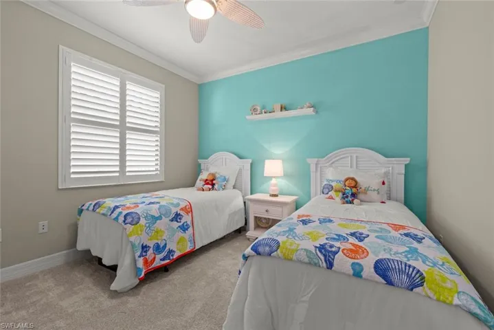 Guest bedroom with a window with white plantation shutters, crown molding, and ceiling fan