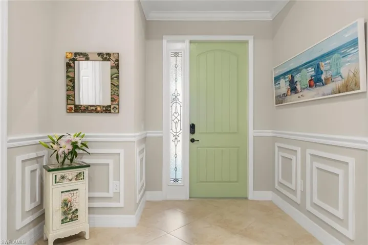 Light-colored entry with decorative wainscoting, crown molding, and tiled flooring