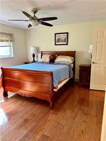 Bedroom featuring hardwood / wood-style floors, a textured ceiling, and a ceiling fan