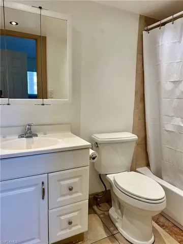 Full bathroom featuring vanity, shower / bath combo with shower curtain, and light tile patterned floors