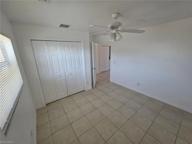 Unfurnished bedroom featuring a closet, ceiling fan, and light tile patterned floors