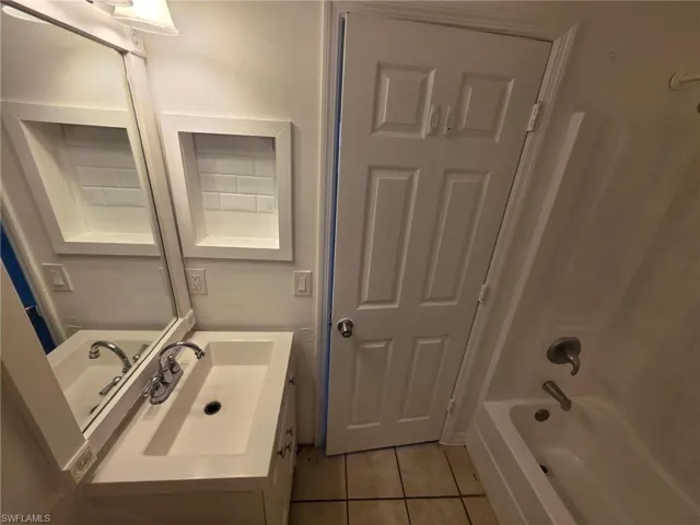 Bathroom featuring vanity, light tile patterned flooring, and shower / washtub combination