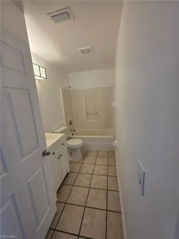 Bathroom featuring vanity, light tile patterned floors, and shower / washtub combination