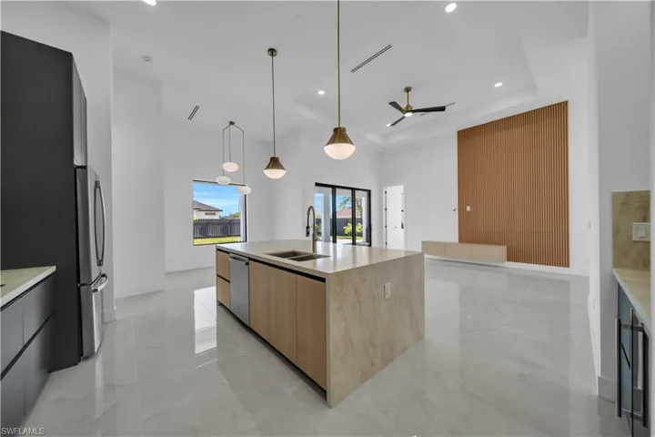 Kitchen with modern cabinets, a sink, stainless steel appliances, a ceiling fan, and light brown cabinets