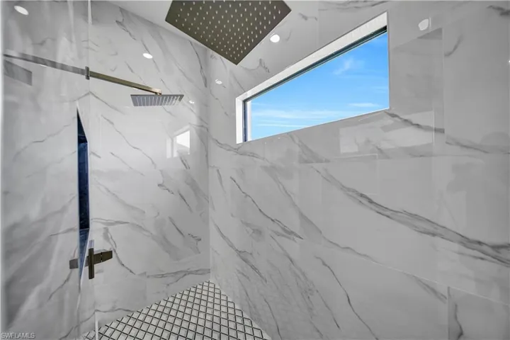 Full bath with a marble finish shower