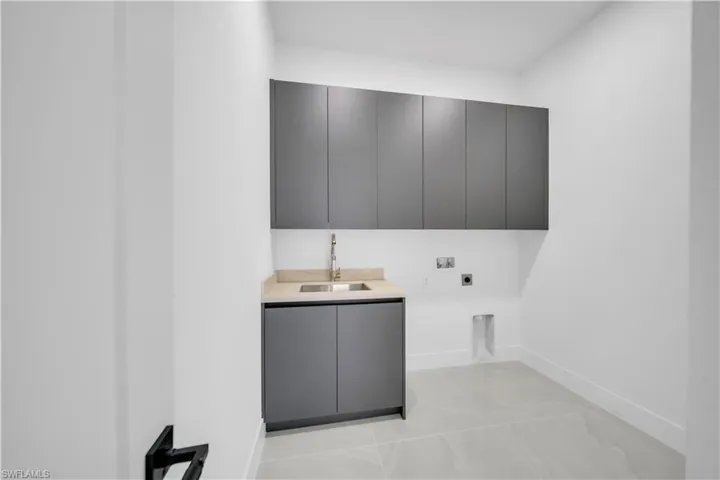 Laundry area with cabinet space, hookup for an electric dryer, and baseboards