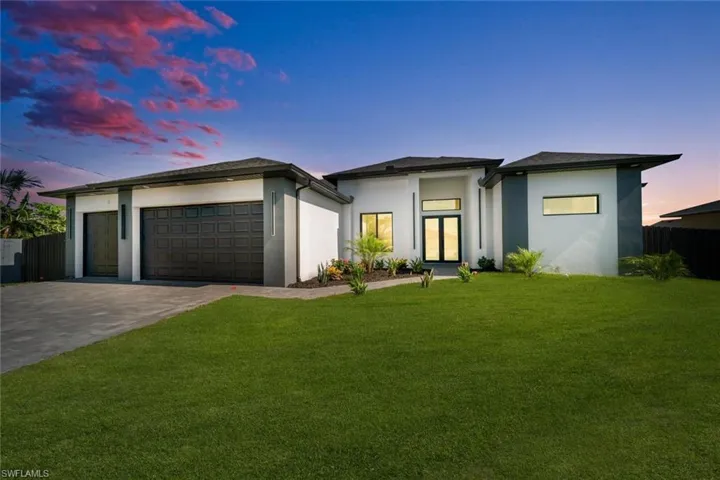 Prairie-style home with stucco siding, a garage, and driveway