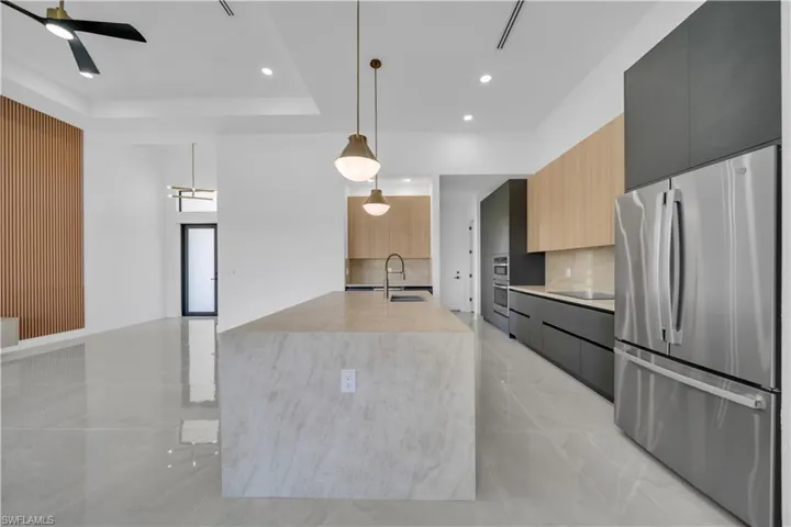 Kitchen with freestanding refrigerator, modern cabinets, light countertops, decorative backsplash, and recessed lighting