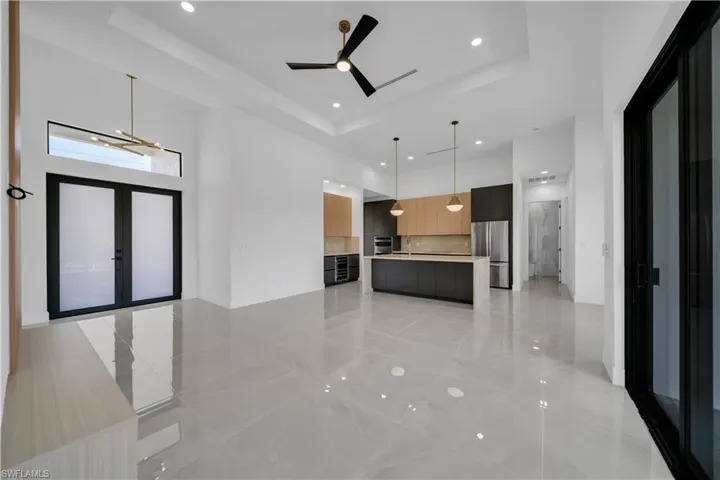 Unfurnished living room with a raised ceiling, a high ceiling, recessed lighting, a ceiling fan, and a sink