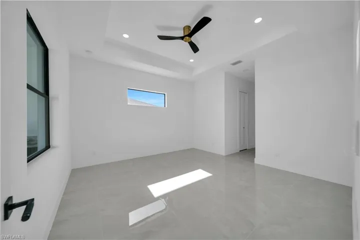 Spare room with a tray ceiling, recessed lighting, a ceiling fan, and baseboards