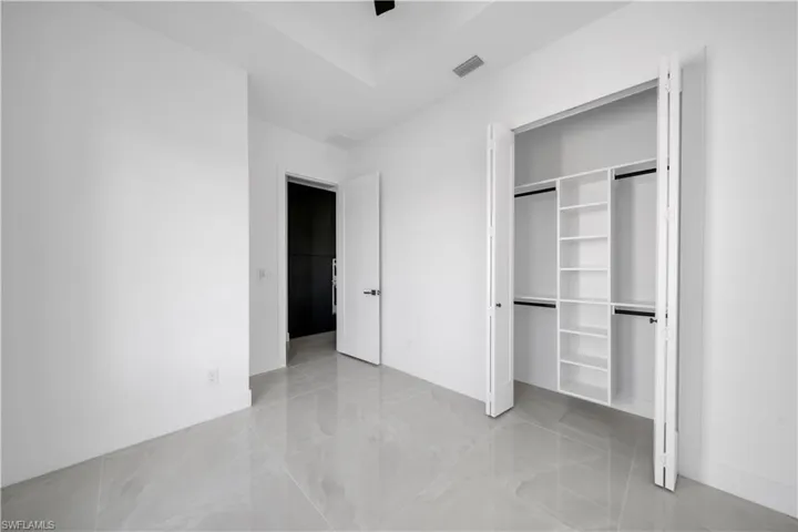 Unfurnished bedroom with a closet, light marble finish floors, and baseboards