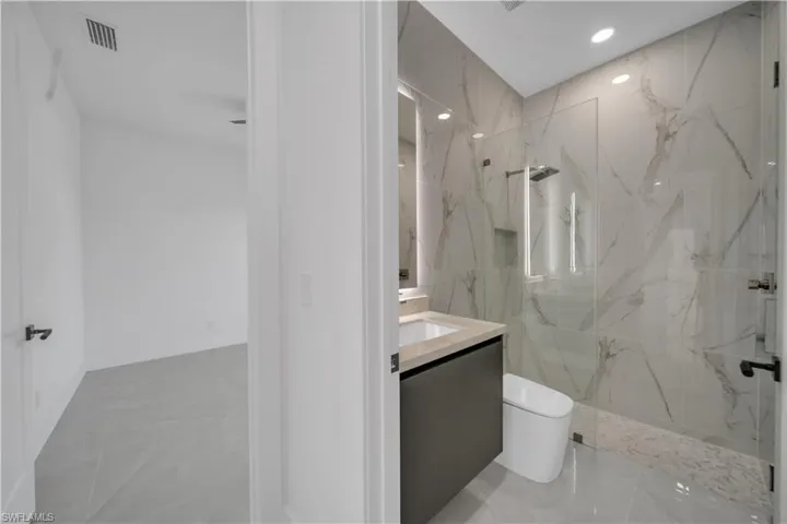 Full bath with toilet, vanity, a marble finish shower, marble finish floors, and recessed lighting