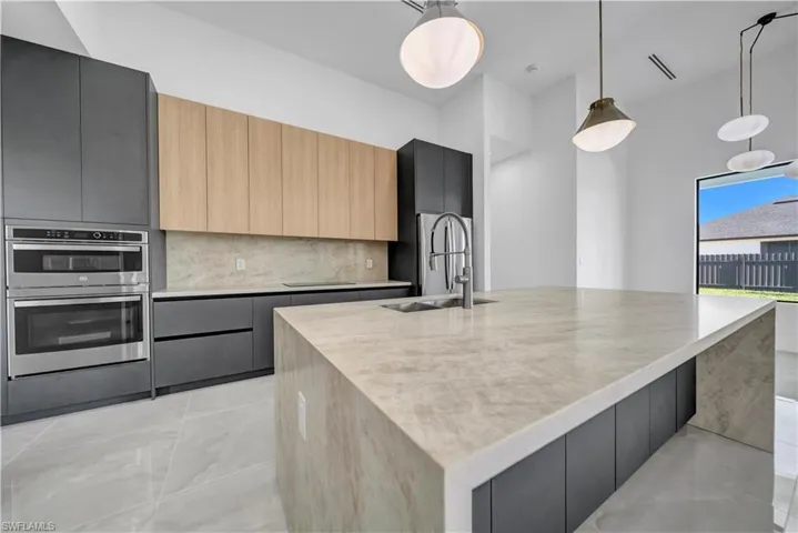 Kitchen featuring a sink, modern cabinets, stainless steel double oven, and a spacious island