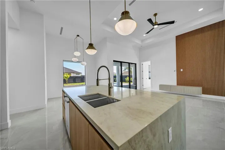 Kitchen featuring a sink, a towering ceiling, dishwasher, modern cabinets, and recessed lighting