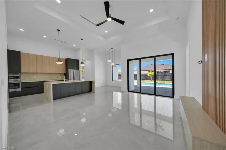 Kitchen with a towering ceiling, modern cabinets, stainless steel appliances, light countertops, and a tray ceiling