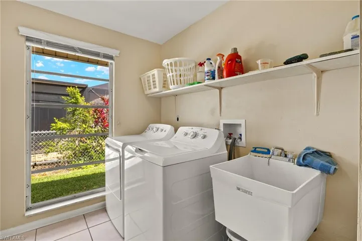 Washroom with light tile patterned flooring and washing machine and clothes dryer