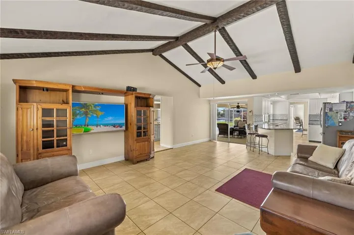 Living room with light tile patterned flooring, high vaulted ceiling, beam ceiling, and ceiling fan