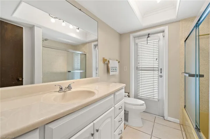 Bathroom featuring vanity, light tile patterned floors, and combined bath / shower with glass door