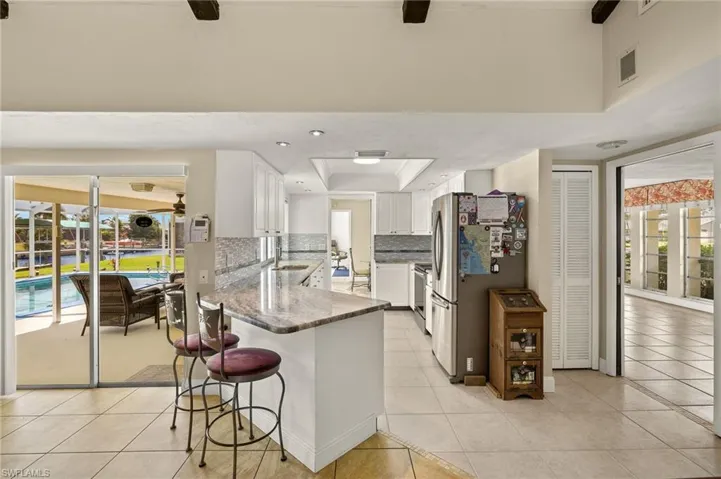 Kitchen with white cabinets, dark stone counters, a kitchen breakfast bar, appliances with stainless steel finishes, and decorative backsplash