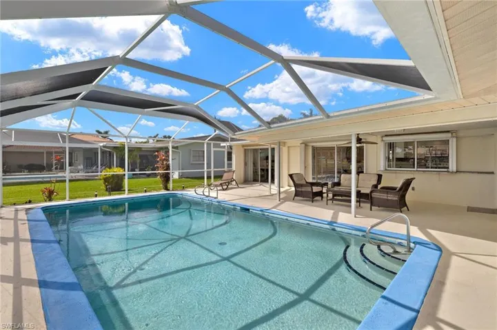 Outdoor pool with a ceiling fan, a sunroom, a patio, an outdoor hangout area, and glass enclosure