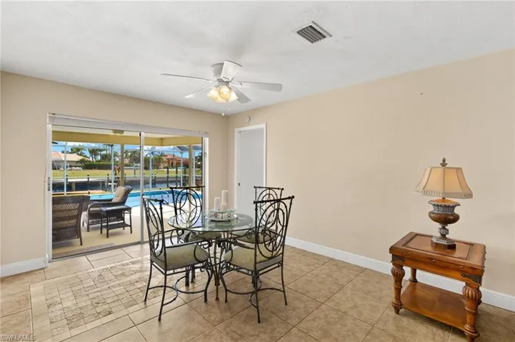 Dining room featuring light tile patterned floors, a ceiling fan, a sunroom, and a water view