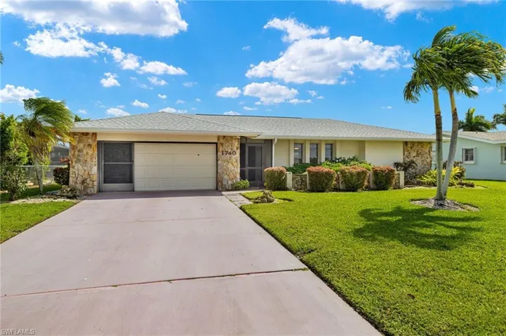 Ranch-style home with stone siding, driveway, a garage, a front yard, and stucco siding