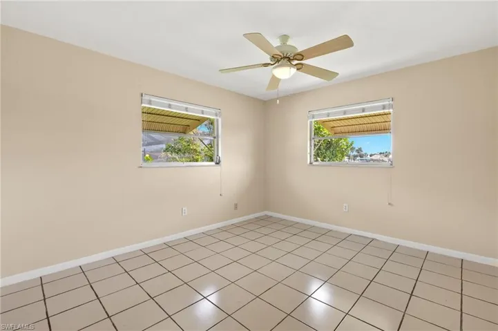 Empty room featuring tile patterned floors and ceiling fan