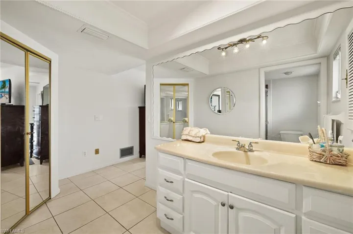 Bathroom with light tile patterned floors, vanity, ornamental molding, and a tray ceiling