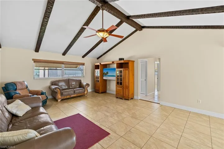 Living area featuring high vaulted ceiling, light tile patterned floors, a ceiling fan, and beamed ceiling