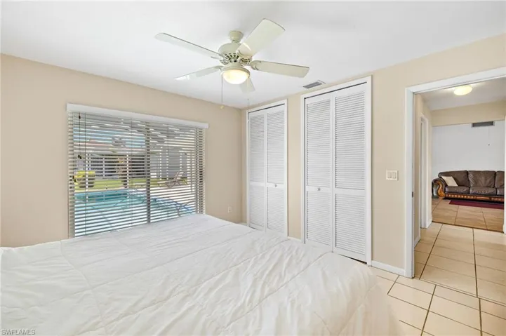 Bedroom with multiple closets, tile patterned flooring, and a ceiling fan